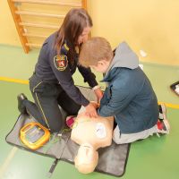 Chłopiec i funkcjonariuszka uciskają klatkę piersiową fantoma